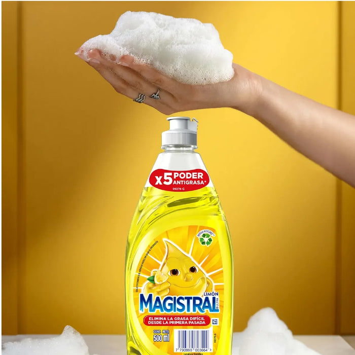 Lavalozas Magistral Limón 500ml — mano con espuma sobre la botella en fondo amarillo con fórmula concentrada aroma limón para loza diaria